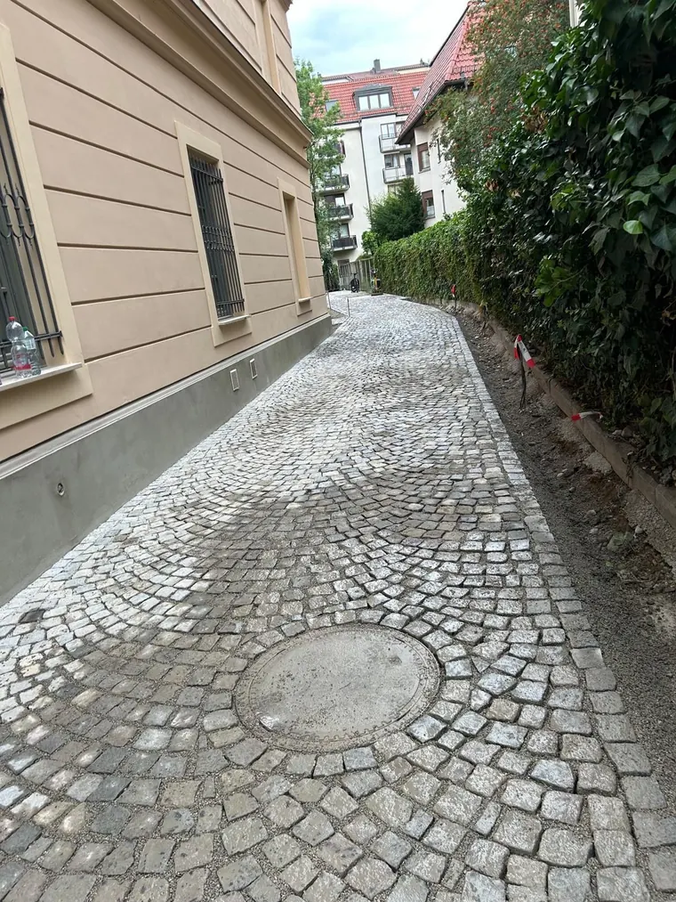 Neben einem Gebäude wird eine Treppe gebaut, im Hintergrund ein Bagger