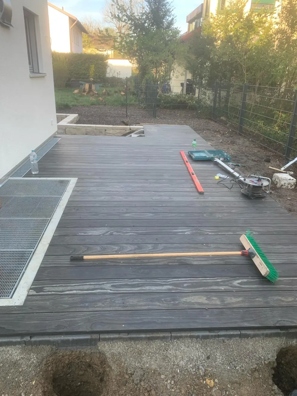 Ein Holzdeck mit Besen und Wasserwaage während der Arbeit